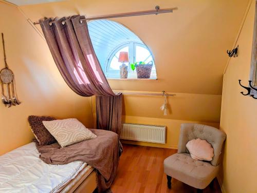 a small bedroom with a bed and a chair at Glemminge Bed & Bastu in Glemminge