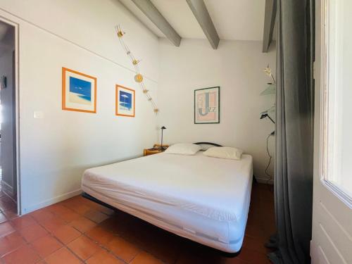 une chambre avec un lit blanc dans une pièce dans l'établissement Maison - piscine - clim - wifi - vue lac - 4 pers, à Fitou