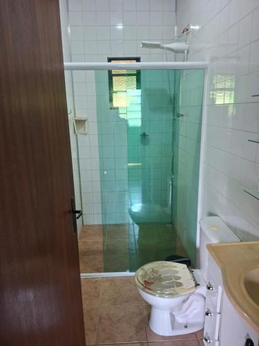a bathroom with a toilet and a glass shower at Chácara Recanto das Águas in Juquitiba