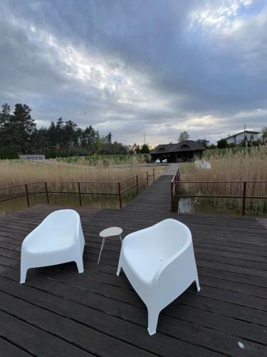 two white benches sitting on a wooden deck at Cabin by the pond in Wądołki Bućki