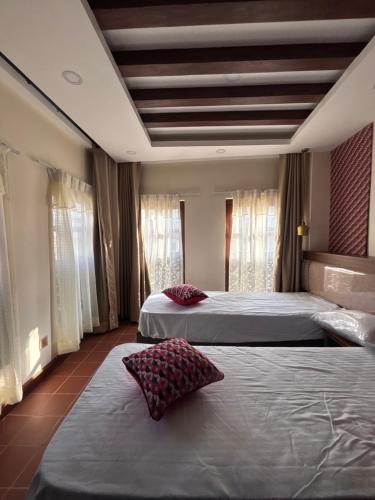 a hotel room with two beds and windows at The Ganesh Kuti in Pātan