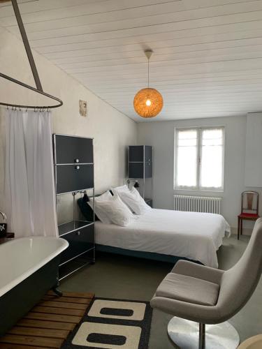 - une chambre avec un lit blanc, une baignoire et une chaise dans l'établissement Maison Face au Soleil, au Bois-Plage-en-Ré