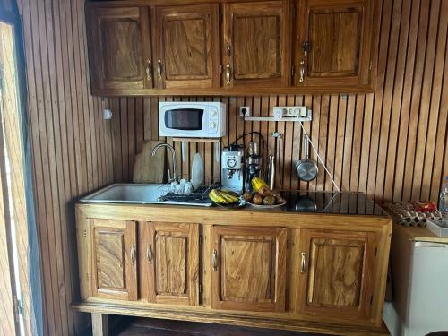 a kitchen with wooden cabinets and a microwave at Kribi-Lodge in Kribi