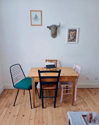 - une table à manger avec des chaises et un ordinateur portable dans l'établissement Appartement de charme centre ville Langeac, à Langeac
