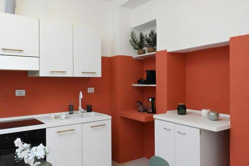 a kitchen with white cabinets and an orange wall at Prestige and comfort in the center of Perugia and views in Perugia