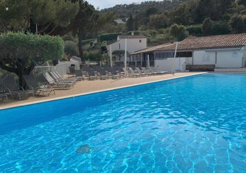une grande piscine bleue avec des chaises et un bâtiment dans l'établissement Les Collines, à Sainte-Maxime