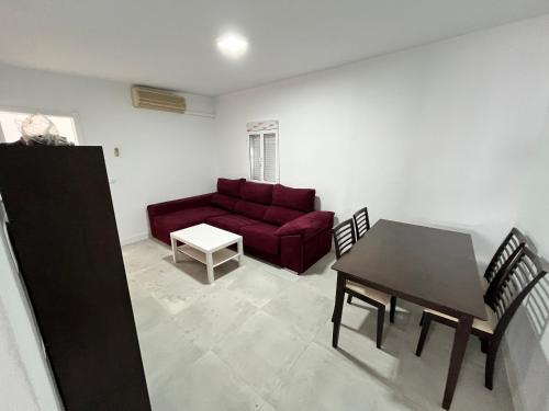 ein Wohnzimmer mit einem roten Sofa und einem Tisch in der Unterkunft Casa Ianira in El Puerto de Santa María