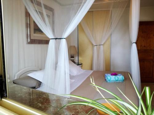 une chambre avec un lit à baldaquin dans l'établissement les pieds dans l'eau, à Roquebrune-Cap-Martin