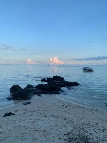 a beach with some rocks in the water at Waka Lodge - House with garden in Blue Bay