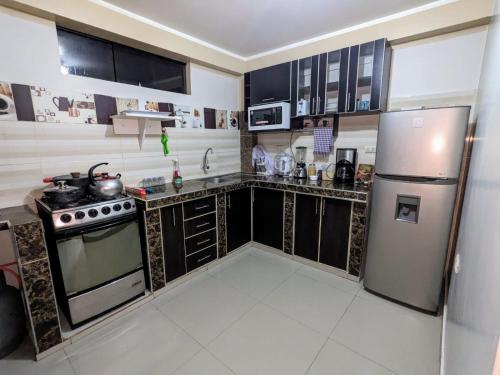 a kitchen with black cabinets and a stainless steel refrigerator at Andes Apartment Sicuani in Sicuani