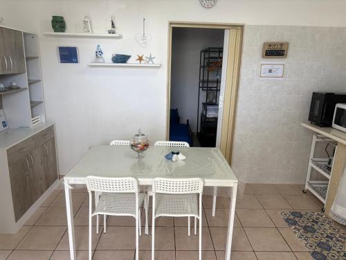 a kitchen with a white table and four chairs at Casa vacanze Santiago e Ian in Maruggio