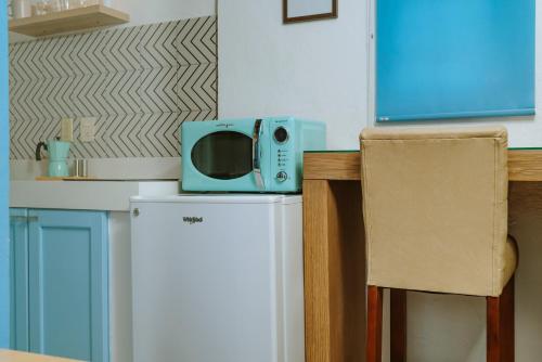 a small blue microwave sitting on top of a refrigerator at Petit Bonheur - Calm Intimate - Terrace & Beach in Puerto Vallarta