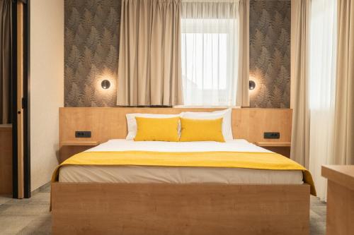 a bedroom with a large bed with yellow pillows at Hotel MANTOVA Vrhnika in Vrhnika