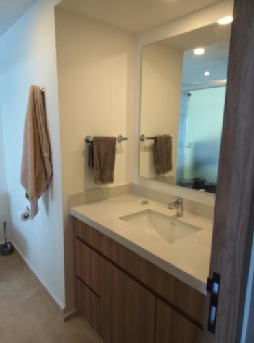 a bathroom with a sink and a large mirror at Beachfront Harbor 171 Condo Ocean View Pool, Gym WiFi in Puerto Vallarta
