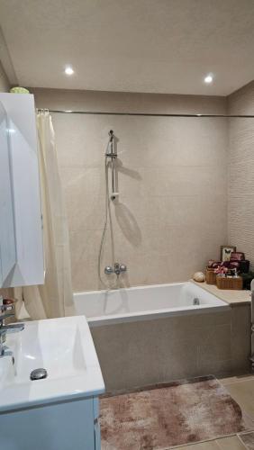 a bathroom with a bath tub and a sink at Coquette appart avec jardin à bousten in Hammamet Sud