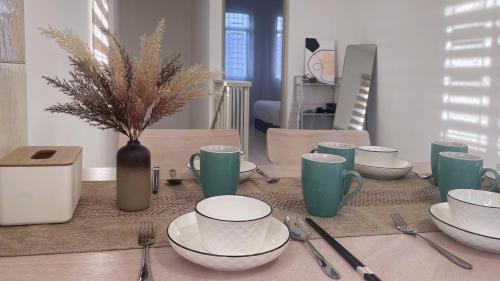 a table with plates and cups and utensils on it at BM IconCity Landed Home by Wemestay - Near AutoCity, Juru, Penang Bridge in Bukit Mertajam