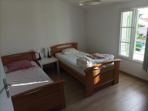 une chambre avec deux lits et deux fenêtres dans l'établissement Maison RIVEDOUX PLAGE 4 chambres à 300m de la plage - climatisée, à Rivedoux-Plage