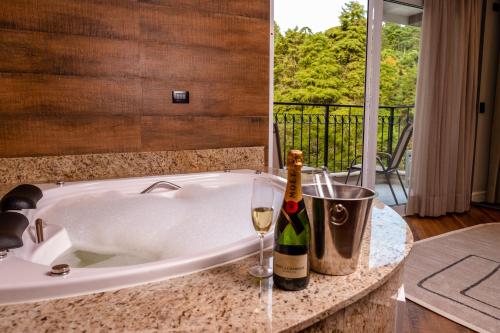 a bath tub with a bottle of wine and a glass at Champet Boutique Hotel in Campos do Jordão
