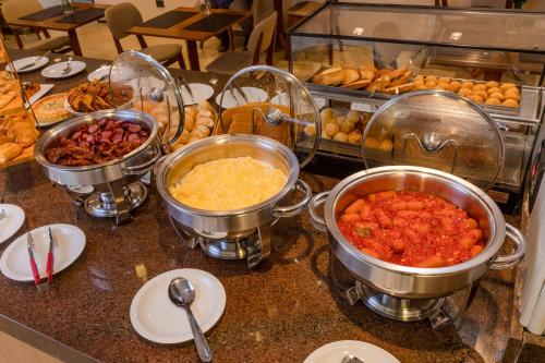 a buffet with several pots of food on a counter at Champet Boutique Hotel in Campos do Jordão