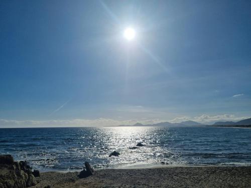 a beach with the sun shining over the water at Diongard House in San Vito