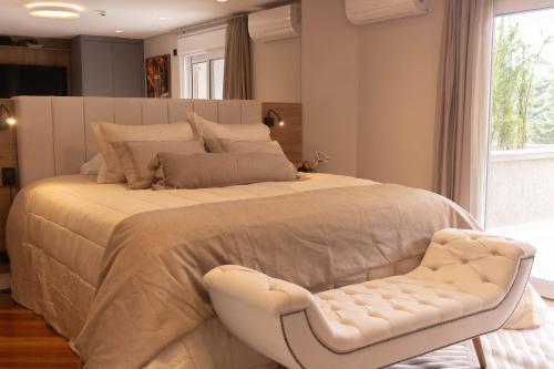 a bedroom with a large bed and a white chair at Champet Boutique Hotel in Campos do Jordão