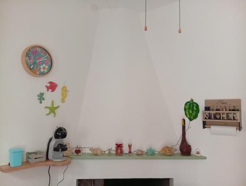 a white wall with a shelf and a clock at Diongard House in San Vito