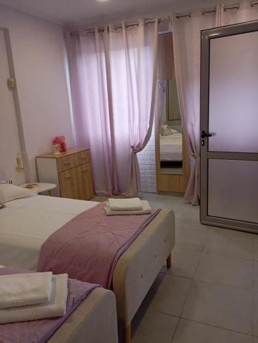 a bedroom with two beds with pink curtains and a mirror at Cozy apartment near to the airport in Kouvarás