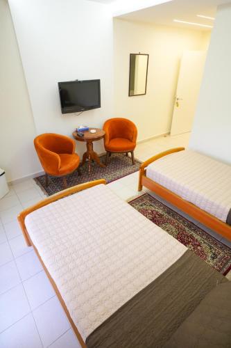 a room with two beds and a table and chairs at Hotel and Restaurant Shallalat Anjar in ‘Anjar