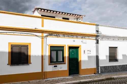 a white building with green doors and windows at Casa da Muralha in Beja