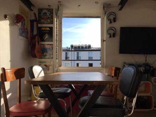 une table et des chaises dans une pièce avec une grande fenêtre dans l'établissement Sunny and serene hideaway in central Paris with AC, à Paris