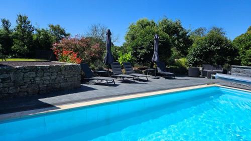 - une piscine avec 2 chaises longues et des parasols dans l'établissement Le Domaine de Keryargon - 2 Gites 3 et 5 personnes, à Belz