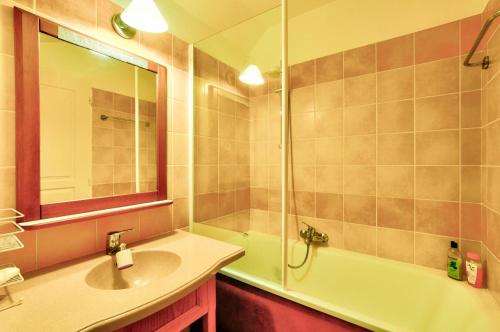 une salle de bain avec un lavabo, une baignoire et un miroir dans l'établissement La résidence du Lac - maeva Home - Appartement 2 pièces 5 personnes - Sélection MAE-2201, à Monflanquin