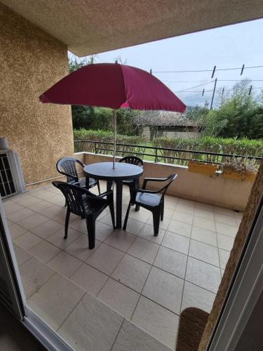 un patio avec une table, des chaises et un parasol dans l'établissement 2 pièces proche mer et commerces, à La Celle-sous-Gouzon