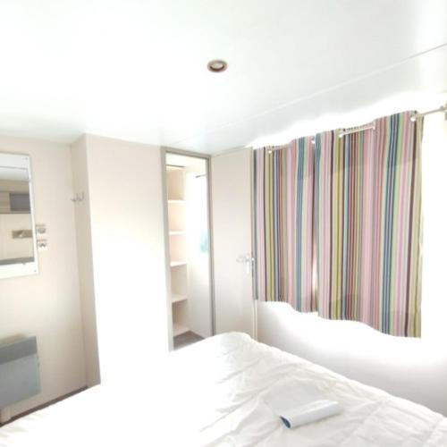 una camera da letto con un letto bianco e uno specchio di Mobilhome 6 personnes a Douarnenez