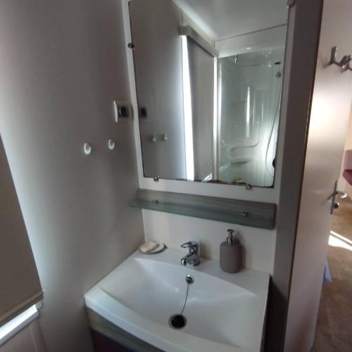 une salle de bain avec un lavabo blanc et un miroir dans l'établissement Mobilhome 6 personnes, à Douarnenez