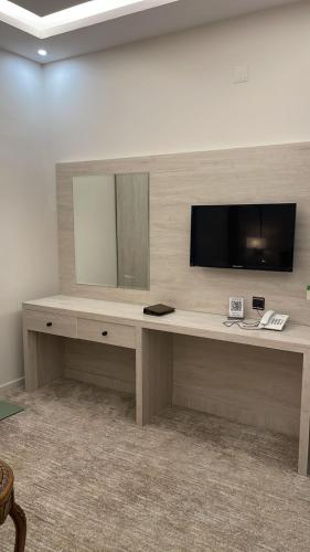 a desk with a television on a wall at فندق أمواج روفا in Şāmitah