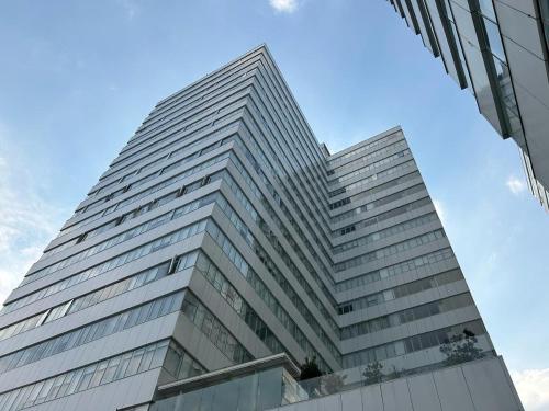 a tall glass building with a blue sky in the background at Centro Banamex Hipódromo de las Américas Toreo in Mexico City