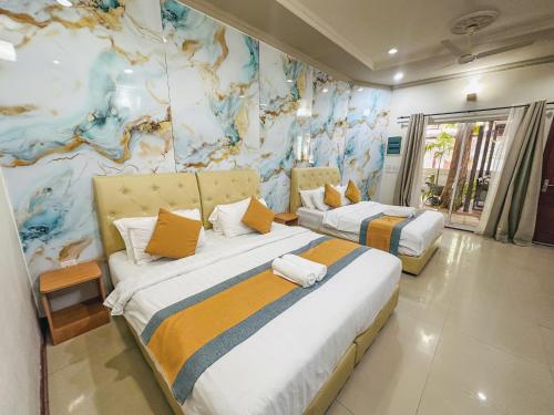 2 letti in una camera con un dipinto sul muro di Lacasa Villa a Ukulhas