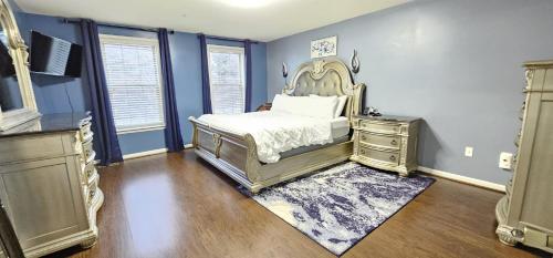 a bedroom with a bed and a dresser and blue walls at Luxury Living at Woodmore in Bowie