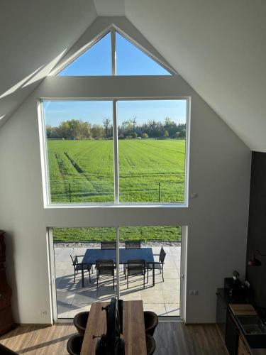 - une grande fenêtre dans le salon avec une table dans l'établissement Les Villas du Ried, à Daubensand