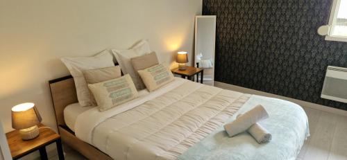 une chambre avec un grand lit avec des draps et des oreillers blancs dans l'établissement Gîte la Broceliande, à Blois