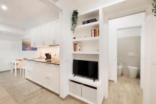 a kitchen with white cabinets and a flat screen tv at La Vega Comfort Stay in Cagliari