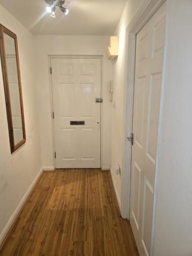 an empty hallway with a white door and wooden floors at Private Room in Hythe