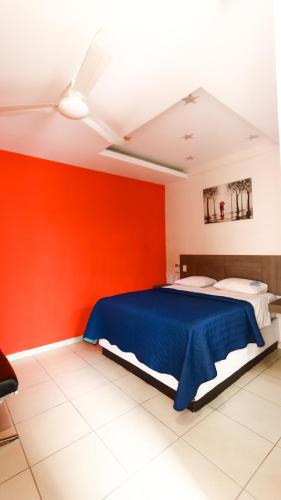 a bedroom with a blue bed and red walls at Hotel Guivá San Pablo in Hacienda Blanca