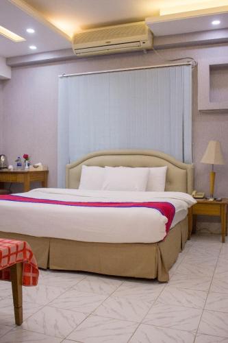 ein Schlafzimmer mit einem großen Bett mit einer weißen Tagesdecke in der Unterkunft Elegant Enchanted in Dhaka