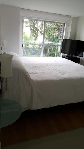 a bedroom with a large white bed and a window at Grupo Kings Suites - Bosque de Duraznos 72 in Mexico City