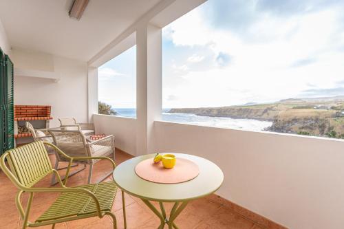 einen Tisch und Stühle in einem Zimmer mit Meerblick in der Unterkunft Eagle's Perch in Porto Formoso in Porto Formoso