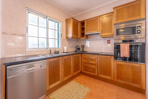 a kitchen with wooden cabinets and stainless steel appliances at Eagle's Perch in Porto Formoso in Porto Formoso