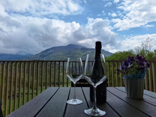 a bottle of wine and two wine glasses on a wooden table at Loft Panoramico Valle dei Laghi in Vezzano