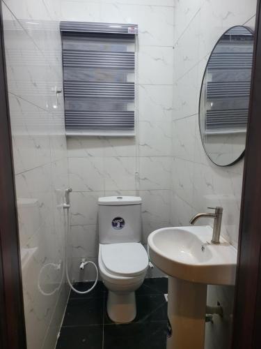 a white bathroom with a toilet and a sink at Kings Heights Apartments in Ikeja